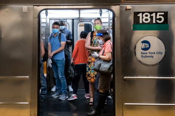 Commuters wearing masks board the subway during morning rush hour in New York. 