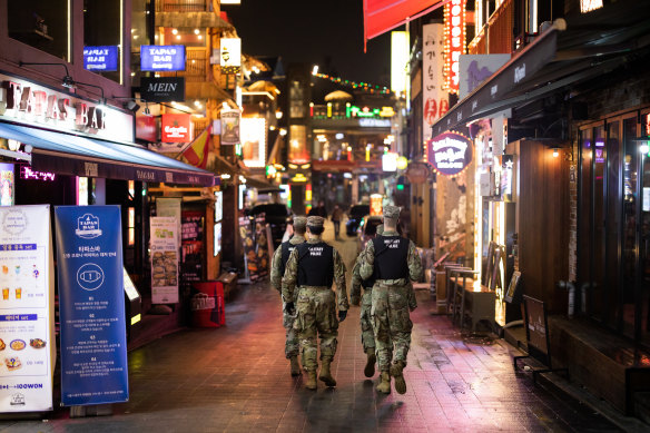 US Army military police patrol the street at night in the Itaewon area of Seoul, South Korea.