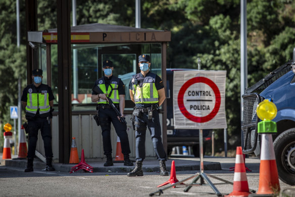 Spanish police officers wait for cars to cross into France at the border checkpoint in El Perthus on Sunday.