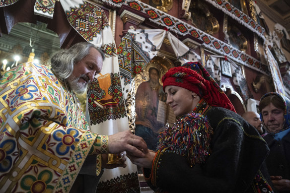 Priest Ivan Rybaruk, left, blesses a woman inside a church during Christmas celebration in Kryvorivnia village, Ukraine.
