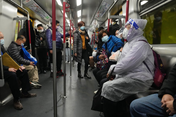 A woman wearing a face mask and face shield, sits in a train in Hong Kong.