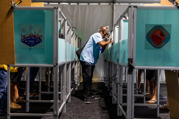 An election official wearing a protective mask and face shield assists voters as they cast their ballot at an early voting polling location in Las Vegas, Nevada.