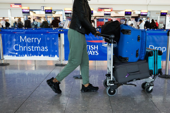 A passenger passes a 'Merry Christmas' sign at a nearly empty check-in area at London Heathrow Airport.