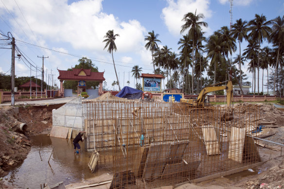 Workers labour on an under construction road outside Ream Naval Base in Sihanoukville, Cambodia.