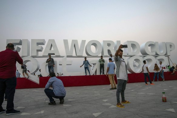 People take photographs in front of a sign representing FIFA World Cup 2022 in Doha on October 21, just 30 days away from the event.
