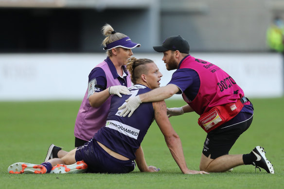 Nat Fyfe of the Dockers receives attention after a heavy knock from Sam Reid.