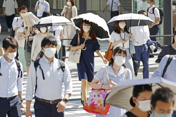 Pazartesi günü Tokyo'da taşıtlar kendilerini güneşten korumak için şemsiye kullanıyor.