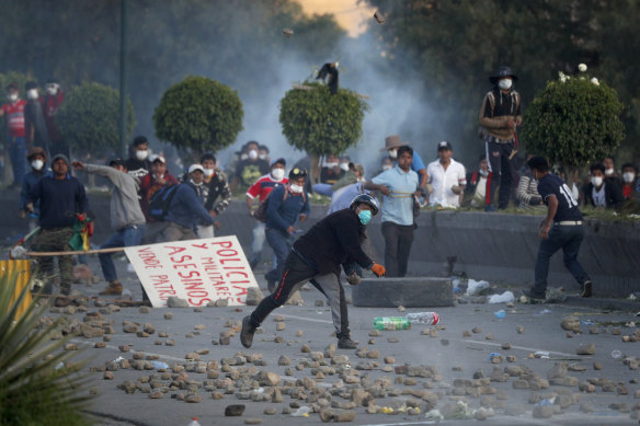 Backers of former president Evo Morales throw stones at police on the outskirts of Cochabamba, Bolivia. Officials now say at least eight people died when Bolivian security forces fired on Morales supporters the day before, in Sacaba.