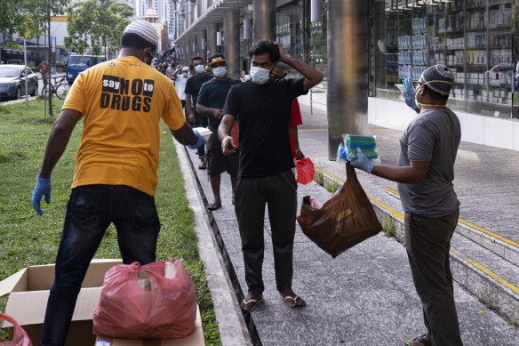 Volunteers distribute food and beverage for free to migrant workers in Little India in Singapore on Saturday. 