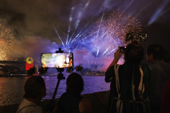 Revellers watch Sydney’s 9pm New Year’s Eve fireworks display from a bar at the Opera House.