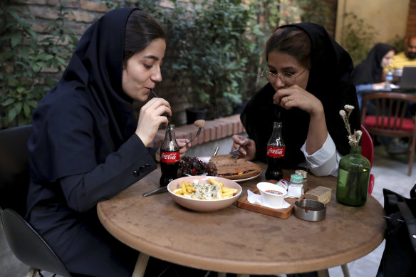Two Iranians drink Coca-Cola at a cafe in downtown Tehran.