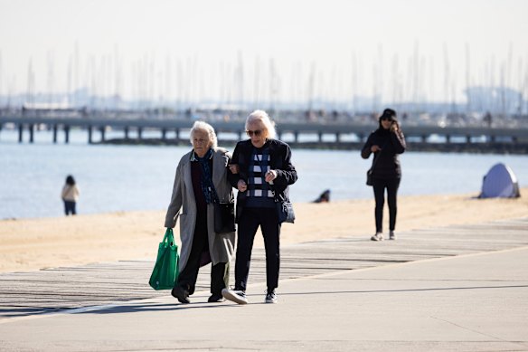 Friends rug up for a stroll along the promenade at St Kilda.