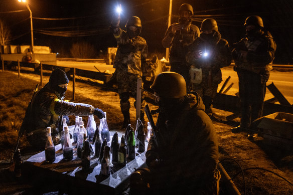 Members of a Territorial Defence unit play checkers with molotov cocktails while guarding a barricade after curfew on the outskirts of eastern Kyiv.