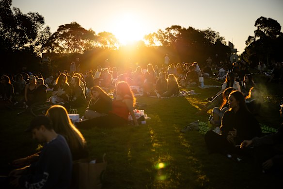 Young revellers sit on picnic blankets at a free public gig at Sydney Park.