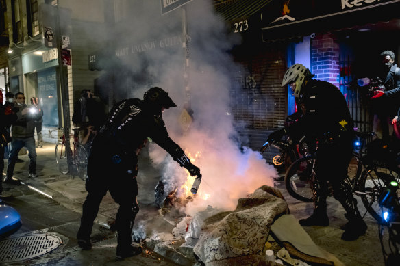 New York City Police officers extinguish a fire at a protest after the election.