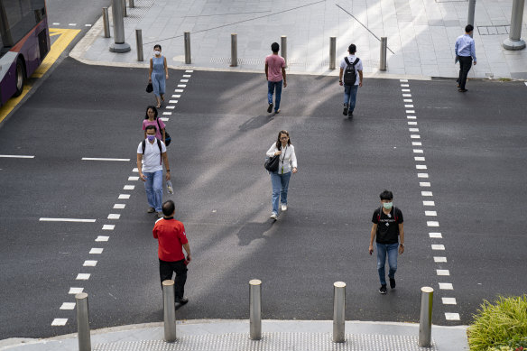 People keep their distance while crossing a road in Singapore to curb the spread of COVID-19.