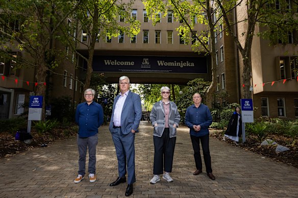 L-R: University of Melbourne professors David Nichols, Christopher Marshall, Alison Young and Philip Goad stand in front of the archway of the John Medley Building. A graduating student poses for a photo behind them.
