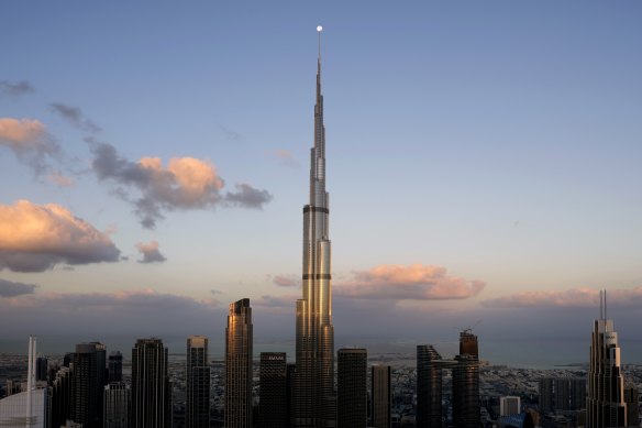 Desert miracle: Dubai skyline with the moon on the tip of Burj Khalifa, the world’s tallest building.