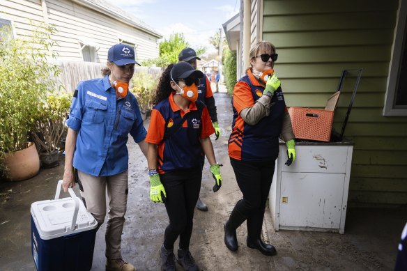 A Disaster Relief Australia official (in blue) attends a Maribyrnong home with community volunteers.