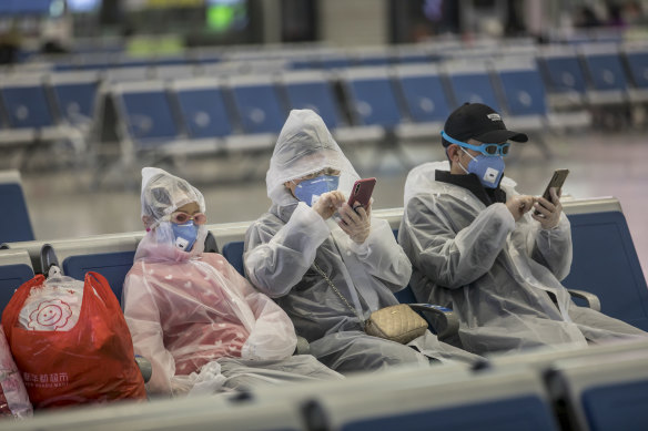 Travellers at a train station in Shanghai wear gear to try to protect themselves from coronavirus.