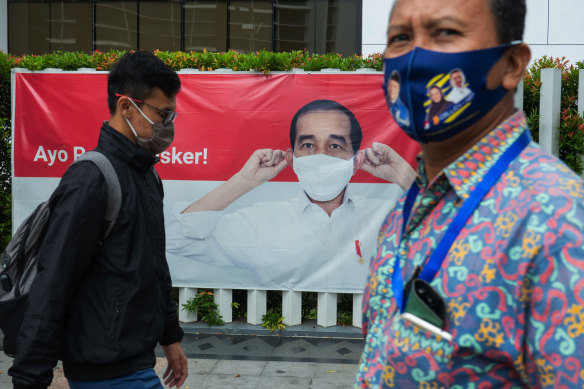 Pedestrians pass a Jakarta poster showing President Joko Widodo, who has said Indonesia's management of the coronavirus "has not been bad".