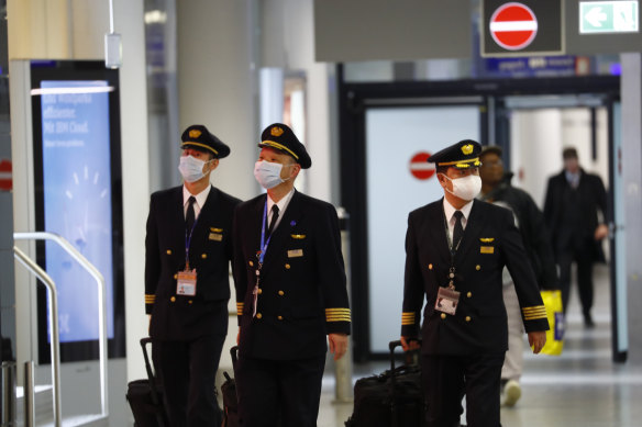 Pilots wear protective face masks while walking through a terminal at Frankfurt Airport.