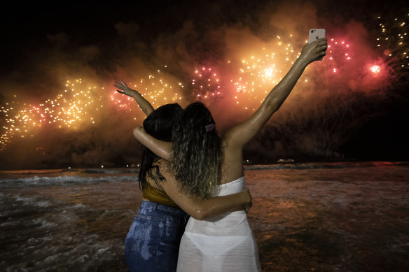 People bring in the New Year as they watch fireworks explode over Copacabana Beach in Rio de Janeiro.