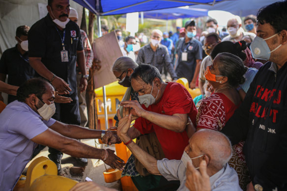 Elderly people struggle in a queue at an entry gate of a COVID-19 vaccination centre in Mumbai.