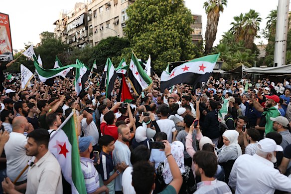 Demonstrators in Damascus wave flags during a rally against Israeli intervention in Syria.