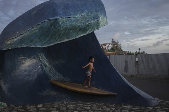 A child plays on a statue of the Teahupoo wave at the end of the road.