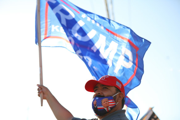 A person in a protective mask waves a flag in support of US President Donald Trump outside at a polling station in Houston, Texas.