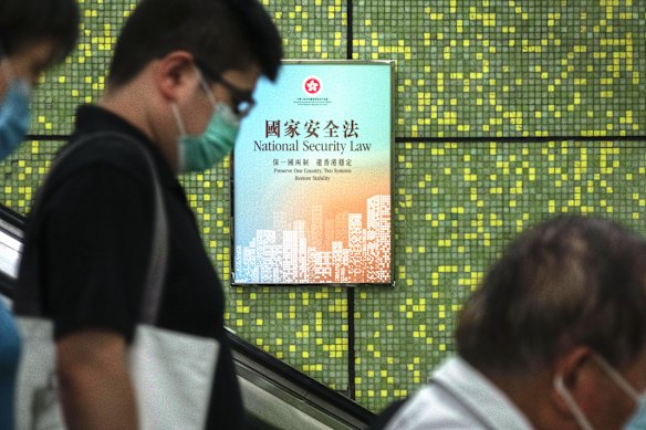 Pedestrians ride an escalator at a train station in Hong Kong where Government National Security Law posters have been plastered on walls.