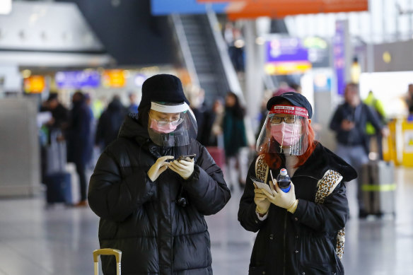 Travellers wear face masks and protective facial visors at Frankfurt Airport.