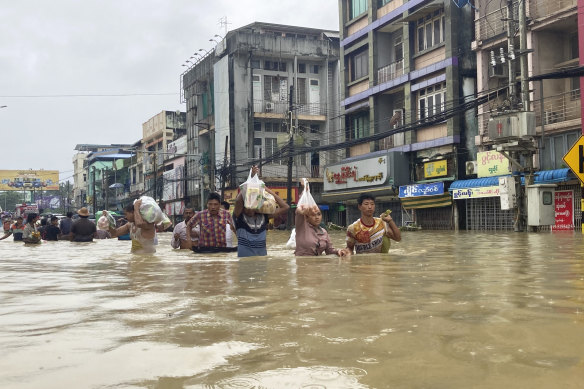 Local residents carrying foods wade through a flooded road in Bago, about 80 kilometres north-east of Yangon, Myanmar, on Tuesday.