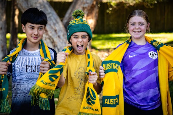 From left: Archie Marigliano, 12, Ari Sutton, 12, and Alice Jeffreson, 12, wear their Socceroos support on their necks, heads and sleeves in Hurlstone Park on Saturday.