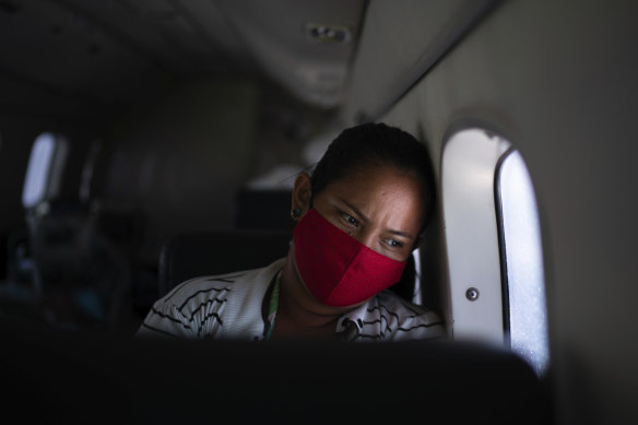 Telma Maria looks out of the window as a doctor monitors her 89-year-old father who is suffering from COVID-19 and is being airlifted to a hospital in Manaus, Brazil.