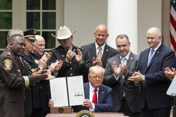 Law enforcement officials applaud after Trump signed the executive order.