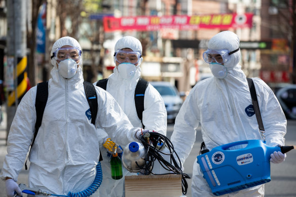 Workers in protective suits disinfect a street in Seoul, South Korea.