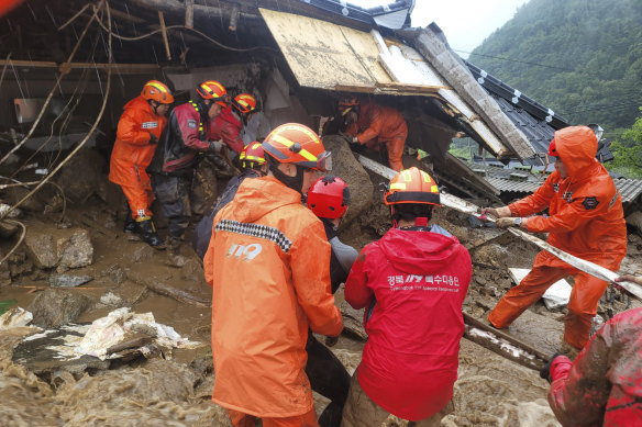 Rescue workers search for people in a house collapsed from a landslide caused by heavy rain in Yeongju, South Korea, on Saturday.