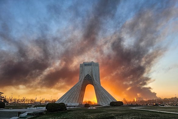 Smoke rises behind Tehran’s Azadi tower after an airstrike.