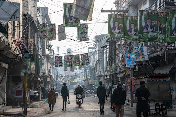 Pakistani residents walk under flags depicting candidates from different political parties ahead of the forthcoming general election.