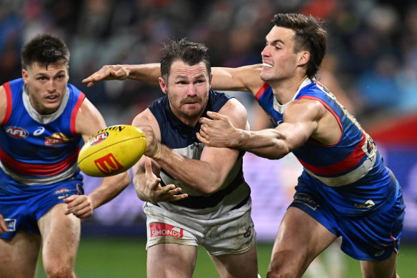 Patrick Dangerfield of the Cats handballs under pressure from Sam Darcy of the Bulldogs.