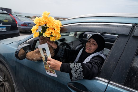 A woman shows a picture of a man alongside flowers placed in a boot as people return to their homes in Southern Lebanon.
