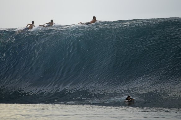 Surfers paddle over the top of a wave in Teahupo’o, Tahiti.