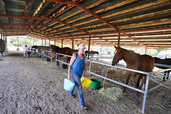 Cloe Rodgerson carries buckets of water for horses in Mansfield.