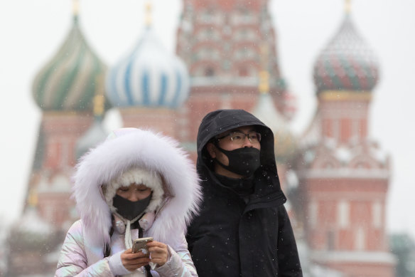 Tourists wear protective face masks as they walk in Red Square near the Kremlin in Moscow, Russia.