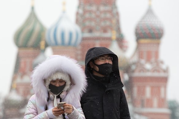 Tourists wear protective face masks as they walk in Red Square near the Kremlin in Moscow, Russia.