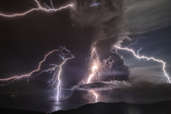 Lightning strikes the erupting Taal volcano through a column of ash.