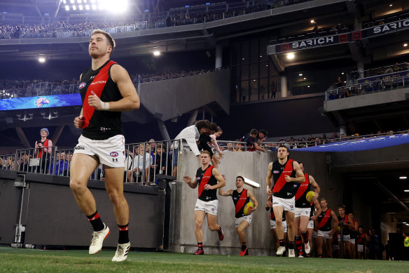 Essendon skipper Zach Merrett leads his team onto Perth Stadium on Saturday night.