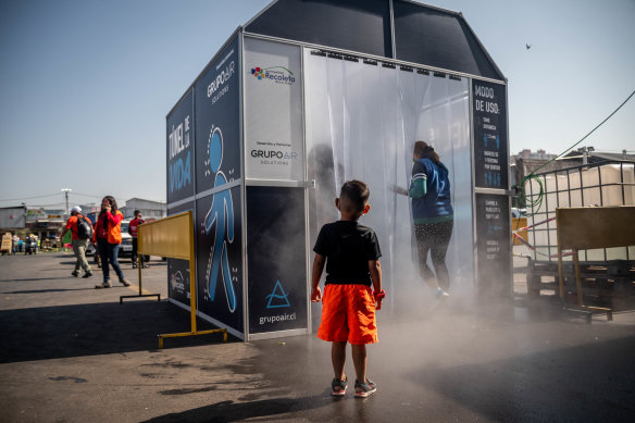 A child watches as people pass through a decontamination chamber at the La Vega Central fruit and vegetable market in Santiago, Chile, in 2020.